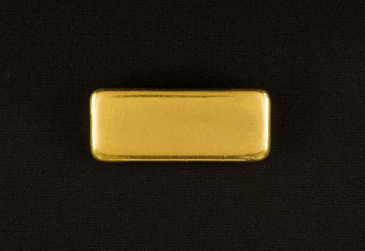 A shiny gold bar with smooth unmarked surfaces and rounded corners, that stands out brightly from a black background
